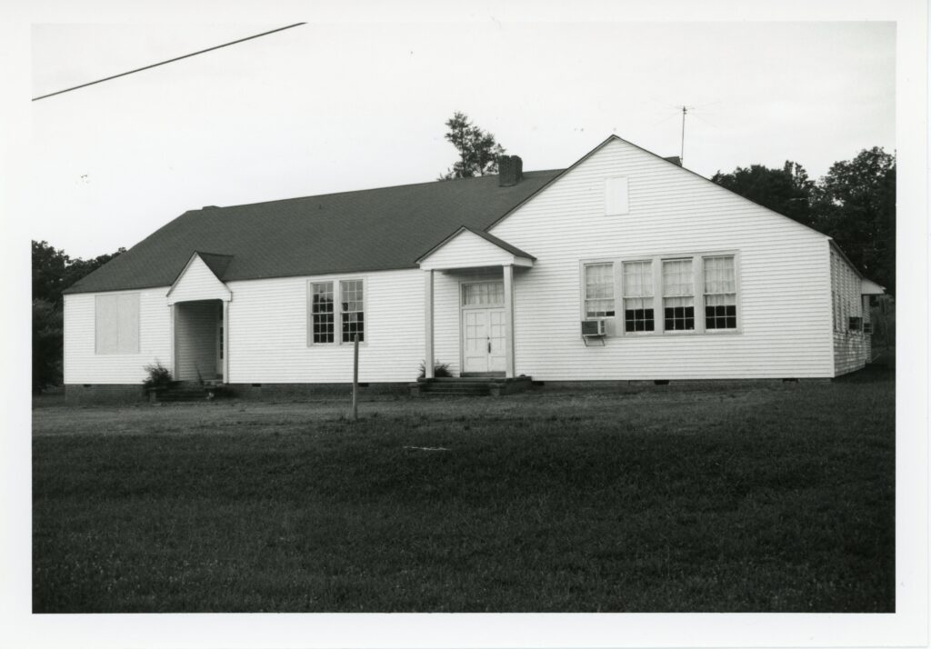 A black and white photograph of a schoolhouse with white clapboard siding.